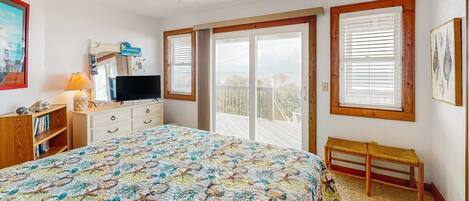 A bedroom with a large bed, a ceiling fan, a TV, a dresser, and a bench.