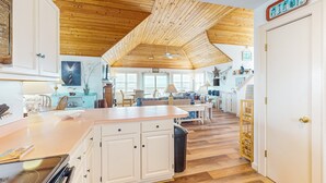 A spacious kitchen with wooden ceiling beams, white cabinetry, and a central island. - Oceanfront dog-friendly home close to sand with views & private hot tub (Buxton)