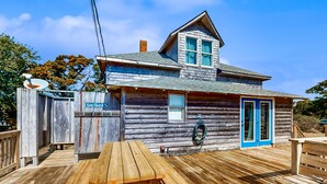 Une cabane en bois dotée d’une terrasse couverte, d’une table de pique-nique et d’un espace douche.