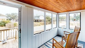Une pièce avec un plafond en bois et de grandes fenêtres, un banc en bois, et une vue sur l’extérieur.
