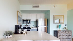 Una cocina con armarios blancos, electrodomésticos de acero inoxidable, una isla central y sillas de madera.