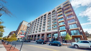 Un hotel de varios pisos con fachada de ladrillo, múltiples balcones y un cielo azul despejado.