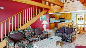 A cozy living room with floral sofas, a white coffee table, and a wooden staircase. - Waterfront, Dog-Friendly House w/Shared Pool, Free WiFi, Private W/D, Central AC (Frisco)