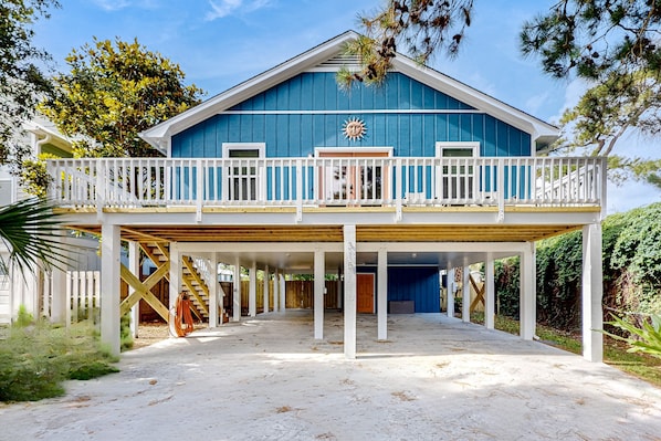 A large house with a blue exterior, a covered porch, and a white fence.