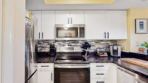 Una cocina moderna con electrodomésticos de acero inoxidable, armarios blancos y un salpicadero de azulejos blanco y negro.