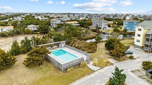 Zona residencial con piscina rodeada de árboles y vista a un cuerpo de agua.