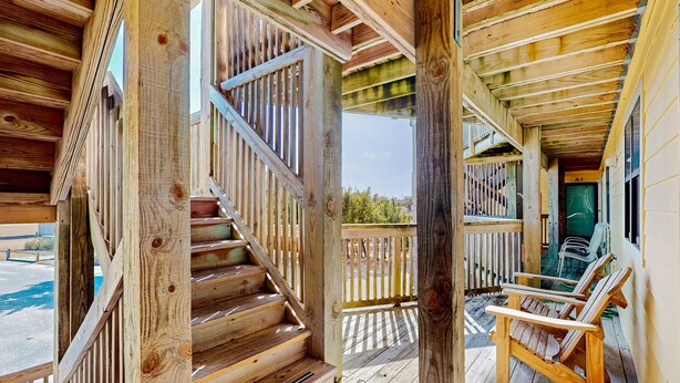 Una terraza de madera con una escalera que lleva a una zona cubierta, una silla y una puerta con la etiqueta "A1".