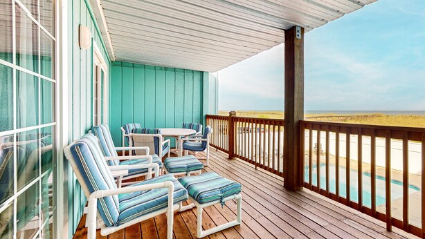 A wooden deck with a pool, a table, and chairs.