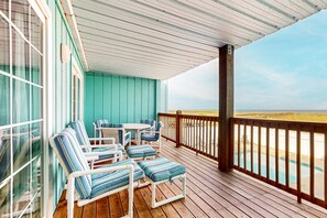 A wooden deck with a pool, a table, and chairs. - Dog-friendly, oceanfront condo with shared pool and beach access (Carolina Beach)