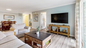 A living room with a sofa set, a coffee table, a TV, and a wooden side table with decorative items.