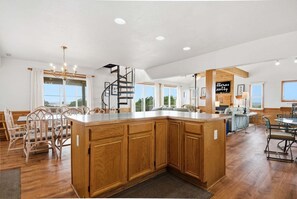 A spacious kitchen with wooden cabinets, a central island, and a spiral staircase.