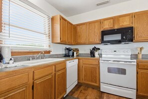 Una cocina con armarios de madera, microondas, estufa y lavavajillas.