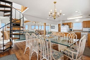 A spacious kitchen with a dining area, featuring a spiral staircase, a chandelier, and wooden cabinets. - Waterfront House w/ Private Hot Tub, Washer/Dryer, Shared Pool, Central AC, WiFi (Frisco)