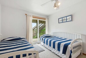 A bedroom with two single beds, a ceiling fan, and a window with curtains.