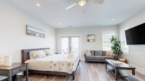 A spacious bedroom with a large bed, a sofa, a coffee table, and a TV. - Oceanview home with close proximity to the beach, AC, W/D, & deck (Carolina Beach)