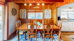 A wooden dining room with a large table and chairs, a ship's wheel, and fish-themed wall decorations. - Beautiful house w/Shared Pool, Private Washer/Dryer, Central AC, Free WiFi (Buxton)