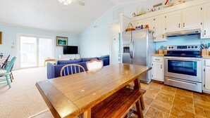 Una cocina moderna con armarios blancos, una mesa de comedor de madera y un horno empotrado.