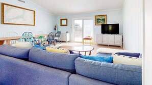 Una sala de estar con sofá, sillas, una mesa de comedor y televisor.