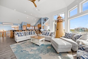 Un vaste salon doté d’un haut plafond, d’un phare en bois et de grandes fenêtres.