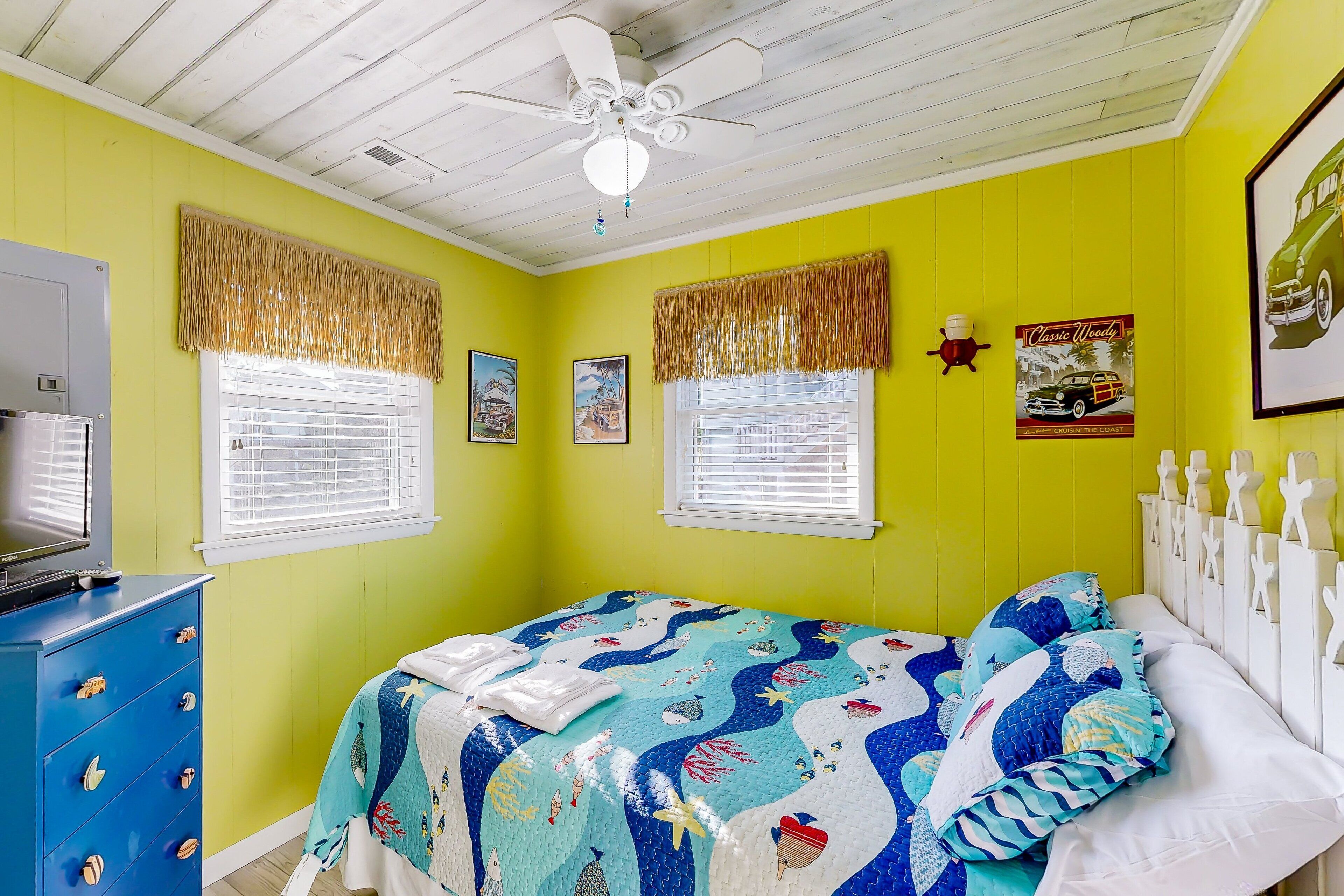 A room with a bed, a ceiling fan, and a window with blinds.
