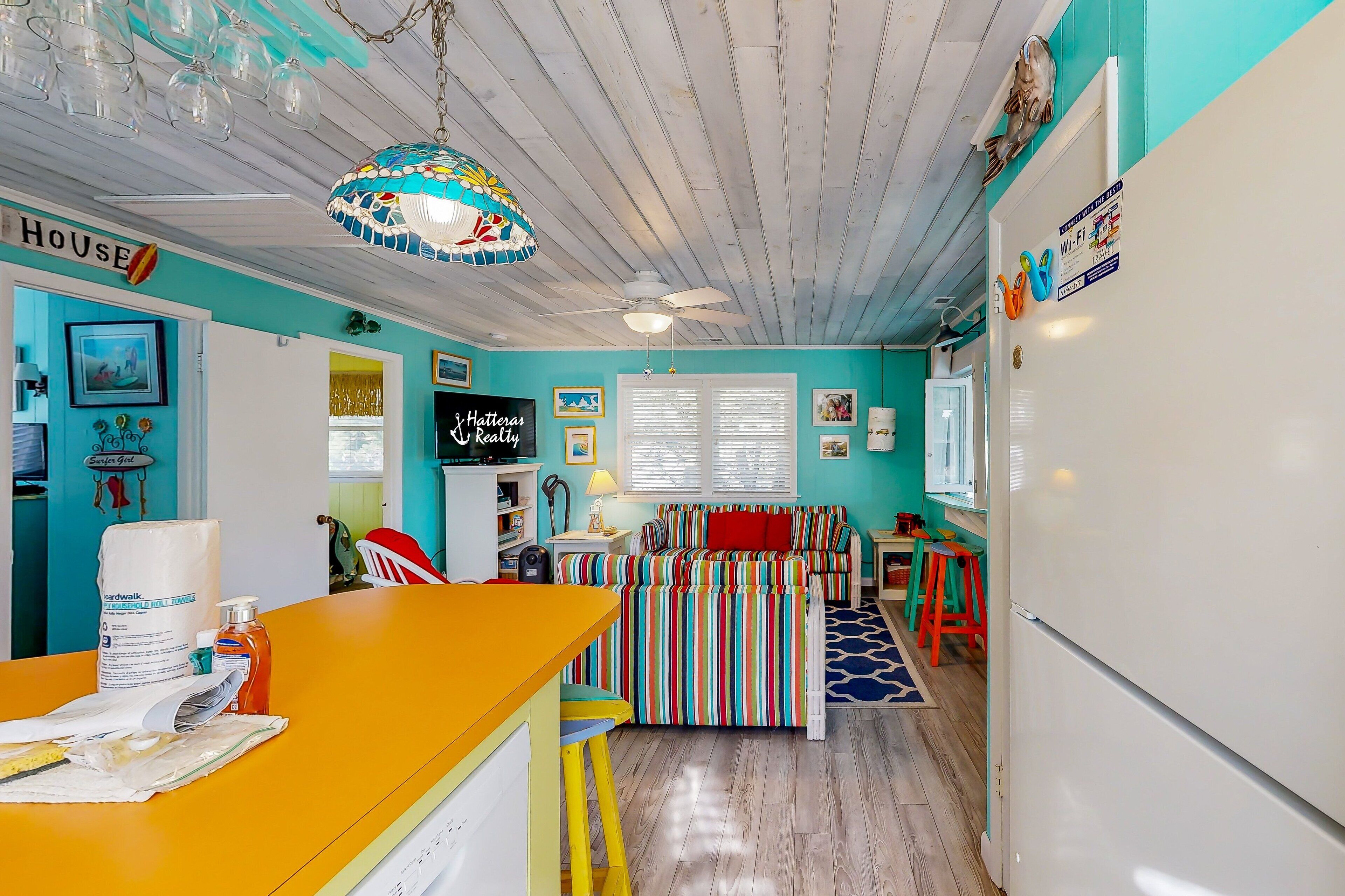 A kitchen with a white refrigerator, a colorful striped sofa, and a ceiling fan.