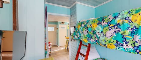 A room with a bunk bed, a desk with a computer, and a chair.