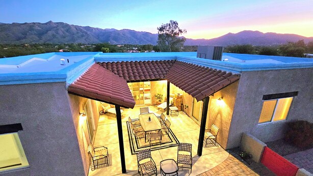 Un patio exterior con zona de comedor, que incluye una mesa y sillas, además de un espacio de descanso cubierto.