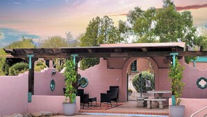Un área de piscina con una pérgola, mobiliario exterior y plantas en macetas.