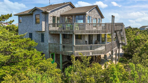 A two-story house with a balcony and a staircase leading to an upper level. - Shallow Point: Creek Views, Expansive decks and Full Kitchen! (Avon)