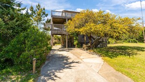 A multi-level wooden structure with balconies, surrounded by greenery and a clear sky. - Shallow Point: Creek Views, Expansive decks and Full Kitchen! (Avon)