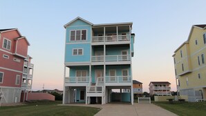 Un immeuble résidentiel à plusieurs étages, doté d’une entrée centrale, de balcons et d’un petit jardin devant.