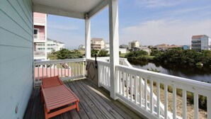 Une terrasse en bois avec une balustrade blanche donnant sur une rivière, entourée d’immeubles d’habitation.