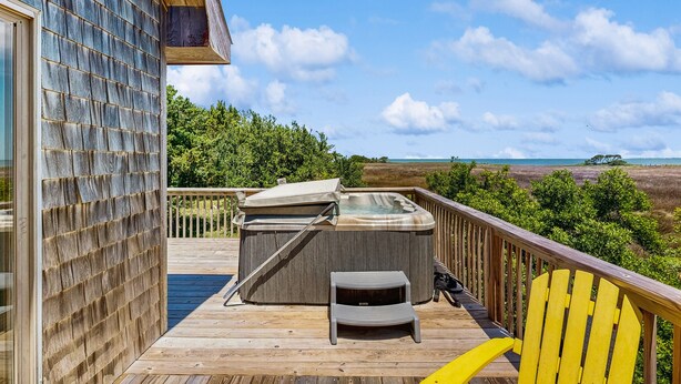 A wooden deck with a hot tub, a small table, and a yellow chair. - Classic home with sound & marsh views, hot tub, decks - near beaches/lighthouse (Frisco)