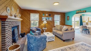 A cozy living room with a fireplace, two sofas, a coffee table, and a 'Welcome' sign. - Classic home with sound & marsh views, hot tub, decks - near beaches/lighthouse (Frisco)