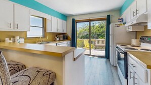 A kitchen with a large window, a sink, and a stove. - Classic home with sound & marsh views, hot tub, decks - near beaches/lighthouse (Frisco)