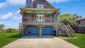 A two-story wooden house with a balcony, a garage, and a staircase leading to the upper floor. - Classic home with sound & marsh views, hot tub, decks - near beaches/lighthouse (Frisco)