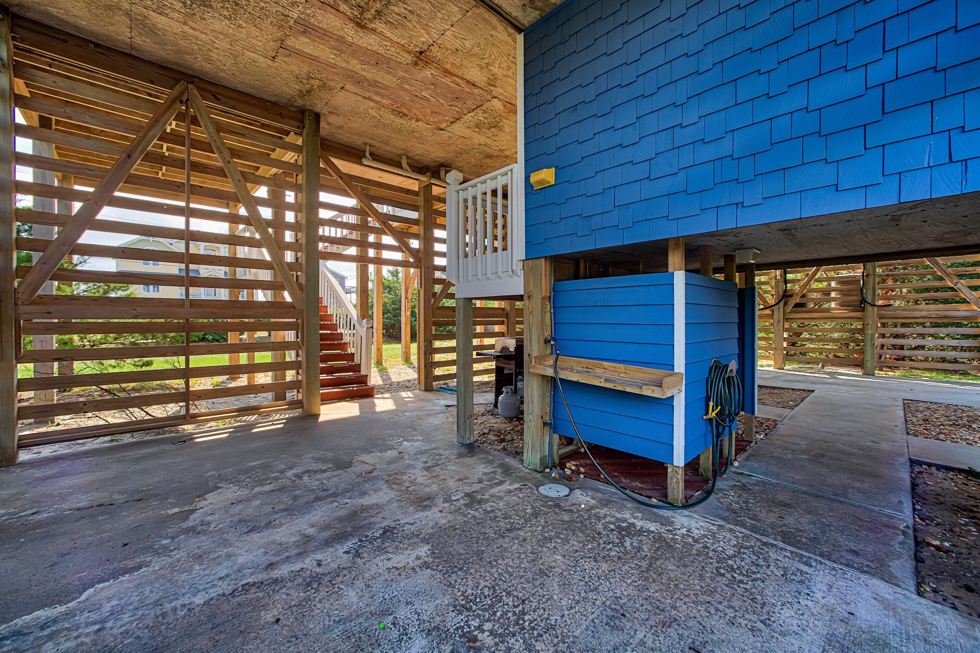 A covered outdoor area with a wooden structure and a blue building.