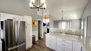 Une cuisine moderne dotée d’un réfrigérateur en acier inoxydable, de meubles blancs et d’un grand îlot central avec un comptoir de couleur claire.