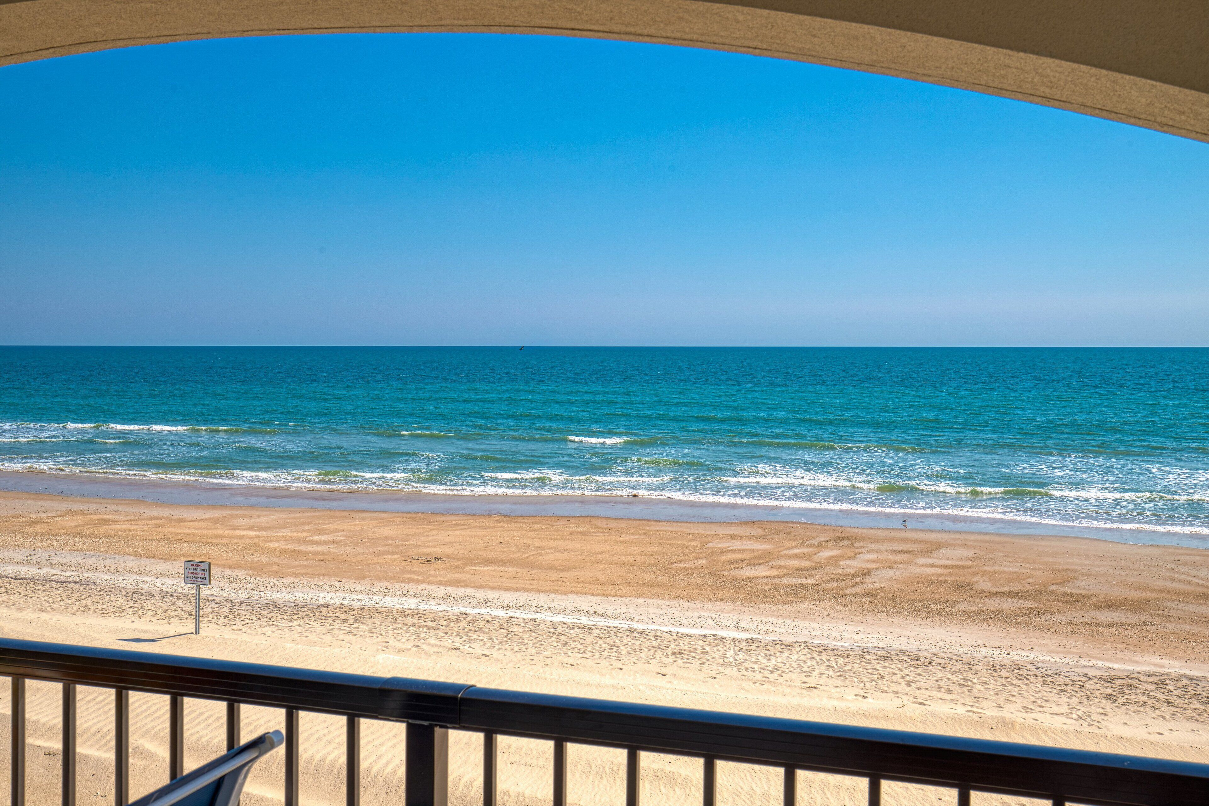 A beach view from a balcony with a clear sky.