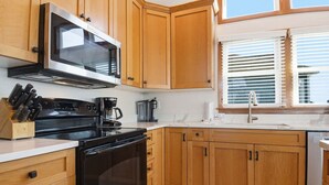 A kitchen with wooden cabinets, a microwave, a stove, and a coffee maker. - Waterfront home with stunning Sound view, private hot tub, pool - 2 dogs OK (Avon)