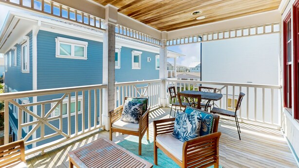 A covered outdoor area with wooden furniture and a view of a blue building. - Beautiful beach house with an elevator, washer/dryer, & AC - walk to the beach (Wrightsville Beach)
