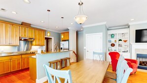 A modern kitchen with wooden cabinets, a stainless steel range hood, and a central island with stools. - Beautiful beach house with an elevator, washer/dryer, & AC - walk to the beach (Wrightsville Beach)