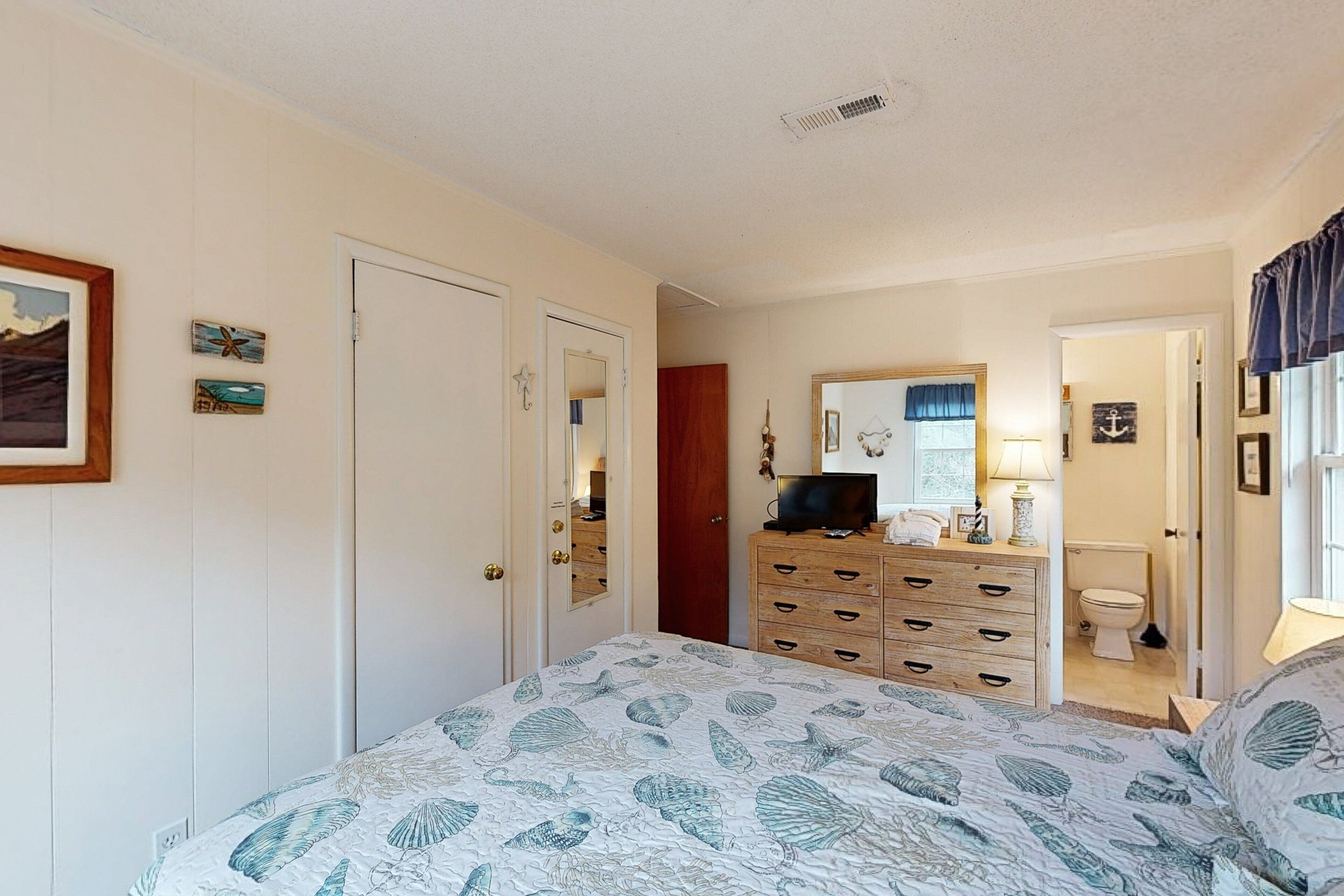 A bedroom with a bed, dresser, and a bathroom visible through an open door.