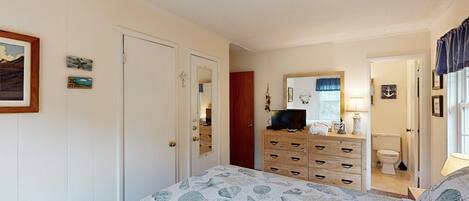 A bedroom with a bed, dresser, and a bathroom visible through an open door.