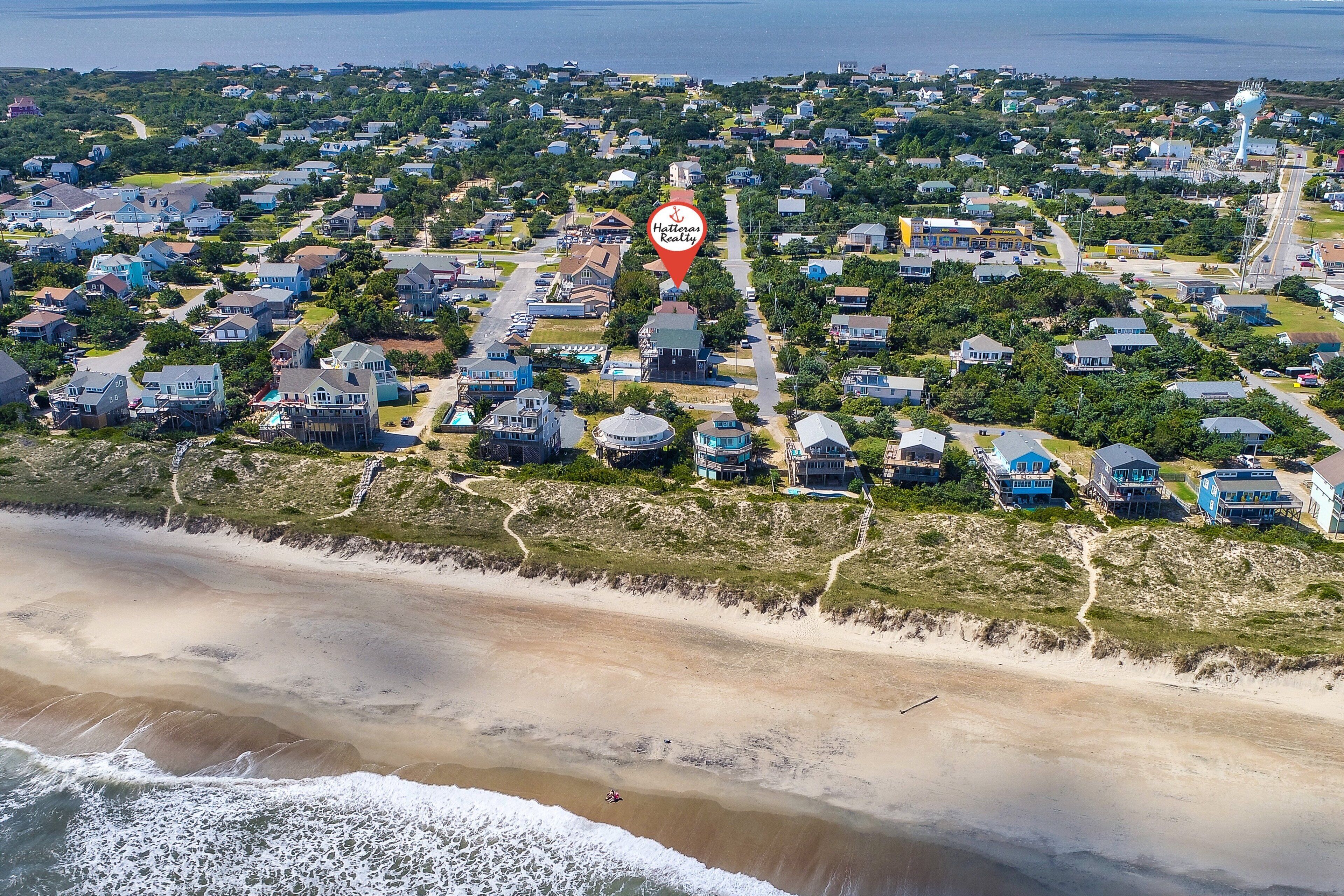 Eine Luftaufnahme einer Küstenwohngegend mit Häusern, einem Strand und einem Leuchtturm.