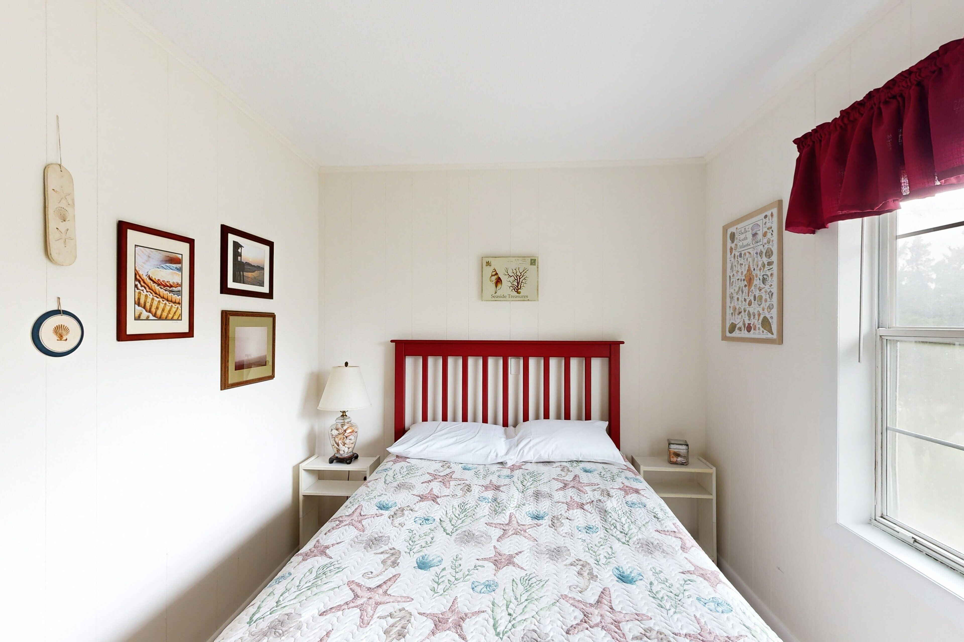 Un dormitorio con cama, mesita de noche, lámpara y ventana con cortina.