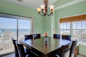 A dining area with a large table, chairs, and a view of the ocean. - Beachfront home with beach access, elevator, ocean views, outdoor shower, W/D (North Topsail Beach)