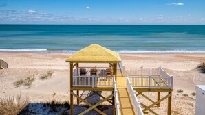 A wooden beach deck with seating and a railing, overlooking a sandy beach and ocean. - Beachfront home with beach access, elevator, ocean views, outdoor shower, W/D (North Topsail Beach)