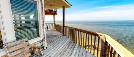 A wooden deck with a bench, overlooking a calm body of water.