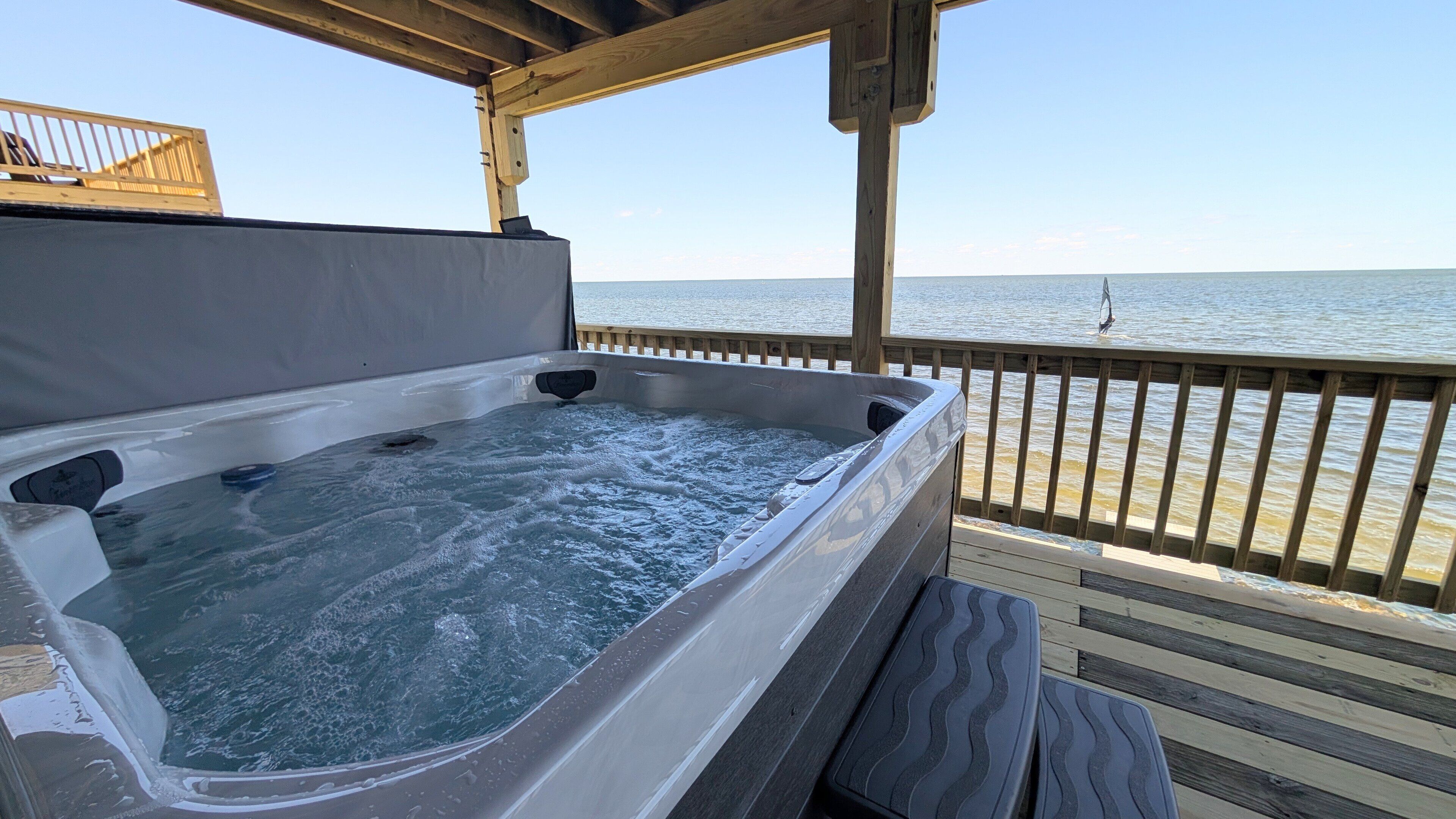 A hot tub on a wooden deck with a view of the water.